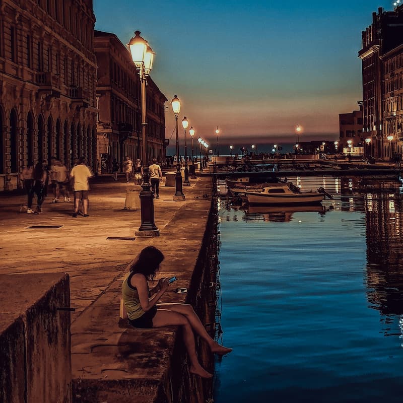 canal(1) trieste grand canal with a person sitting by the adriatic sea next to sailboats